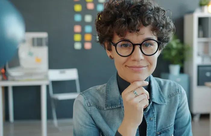 Smiling creative professional with glasses in a denim shirt in a studio, representing global business services